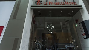 The exterior of Le Prabelle Hotel with a modern glass facade, a prominent entrance, and a visible signboard. - Le Prabelle Hotel (Kowloon)