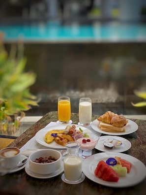 A breakfast table with various food items and drinks, including croissants, fruit, and a glass of orange juice. - Sensa Hotel (Bandung)