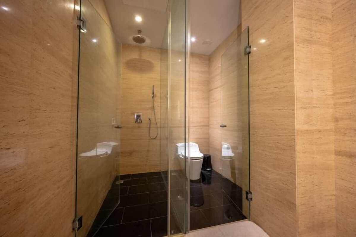 A modern bathroom with a glass-enclosed shower, a toilet, and a sink.