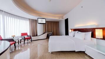Una habitación de hotel moderna con cama, escritorio, silla y televisor.