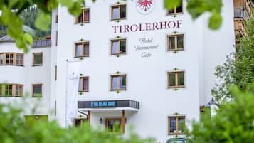 A hotel named "TIROLERHOF" with a sign for "S'NO BLAU BAR" and a logo featuring a red eagle.