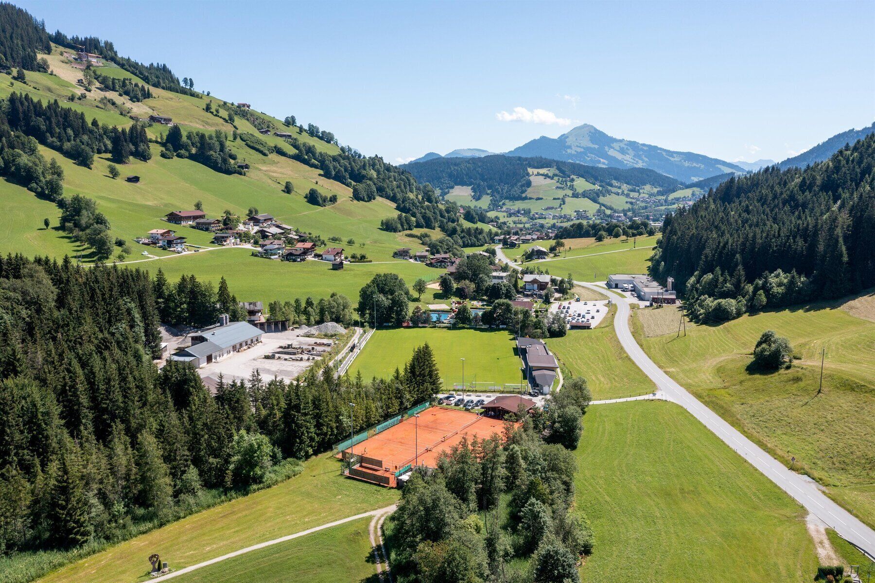 A rural village with houses, a tennis court, and a road.