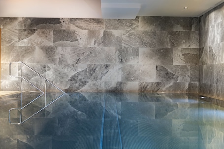 Una piscina techada, sillones reclinables de piscina