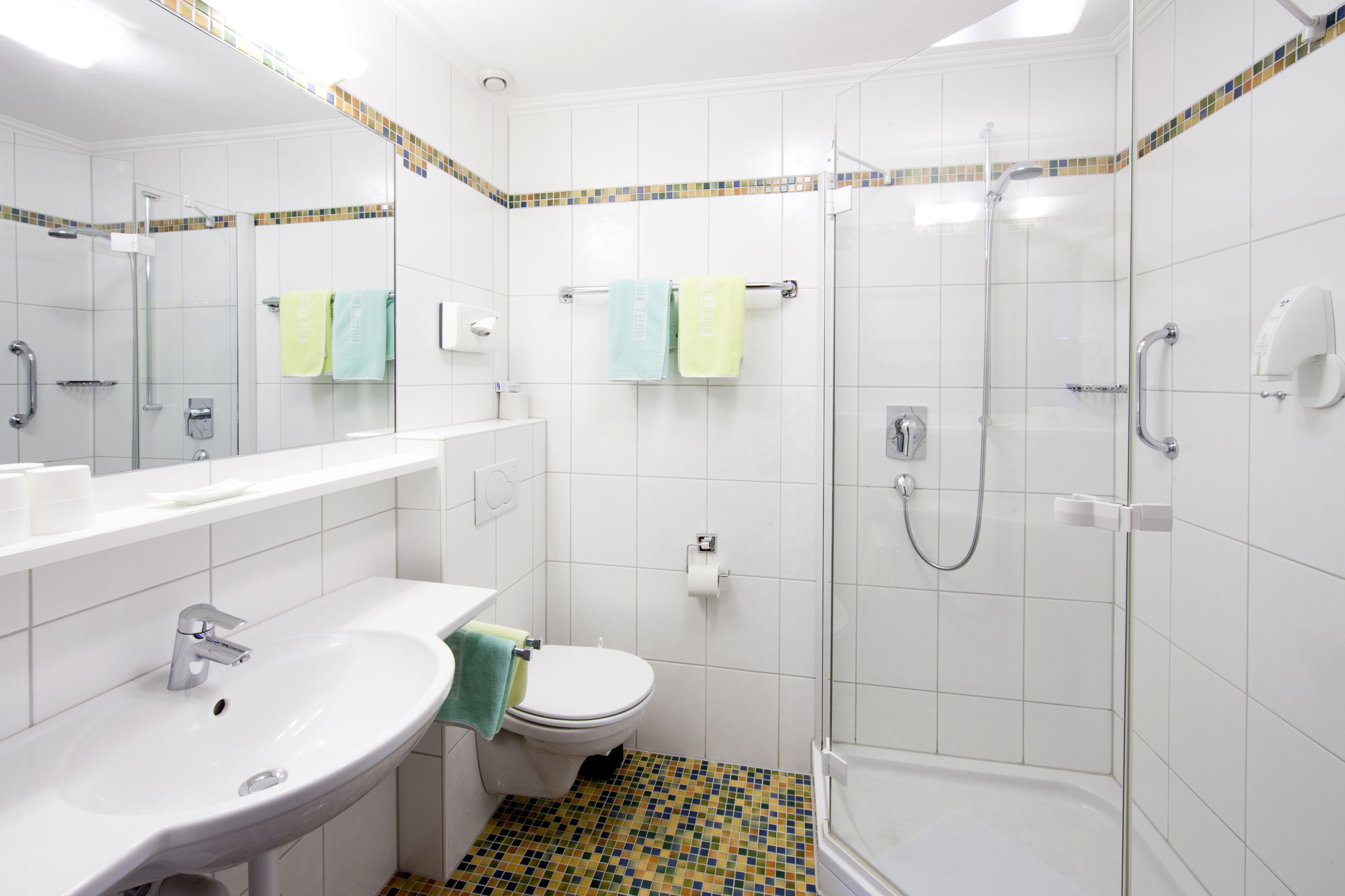 Un baño moderno con lavamanos, inodoro y ducha con mampara de vidrio.