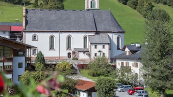 Eine Kirche mit einer grünen Kuppel und einem Glockenturm, umgeben von einer grünen Landschaft und geparkten Autos.