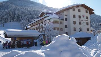 A hotel with multiple floors, a ski lift in the background, and a snowy mountain landscape.