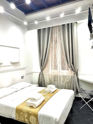 A hotel room with a neatly made bed, a window with curtains, a flat-screen TV, and a ceiling light fixture. - Antica Locanda dell'Orso (Rome)