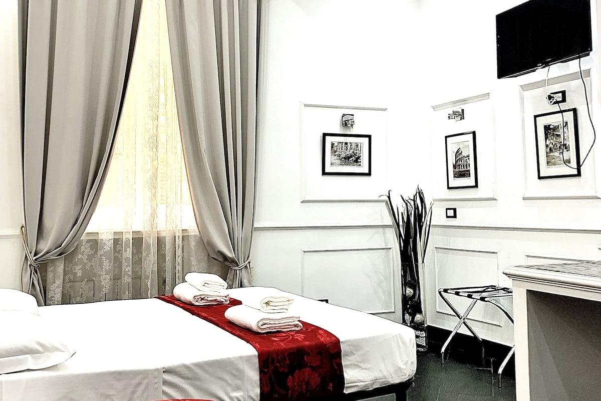 A hotel room with two beds, a desk, and a chair.