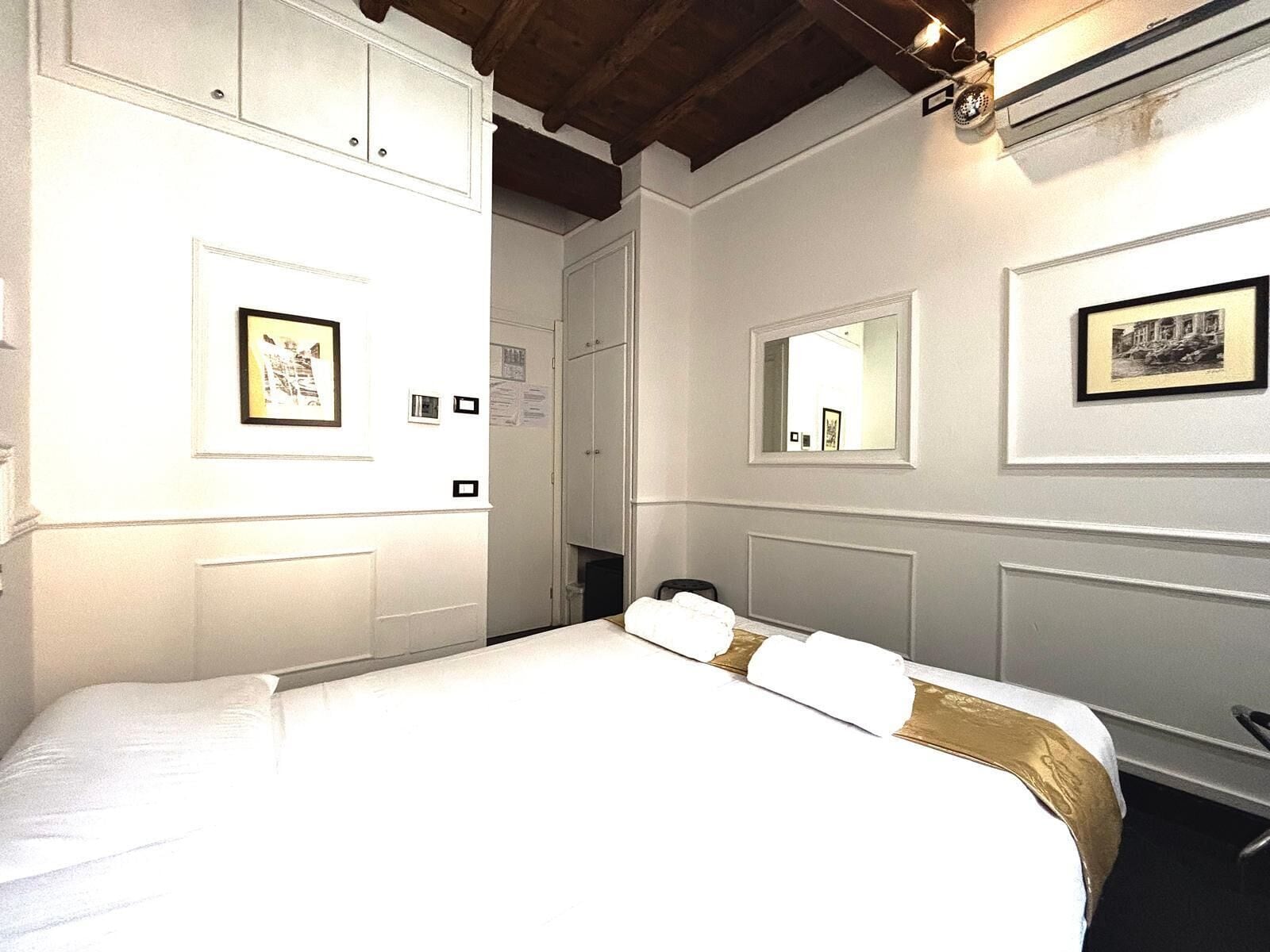 A hotel room with a large bed, a mirror, and framed pictures on the walls.