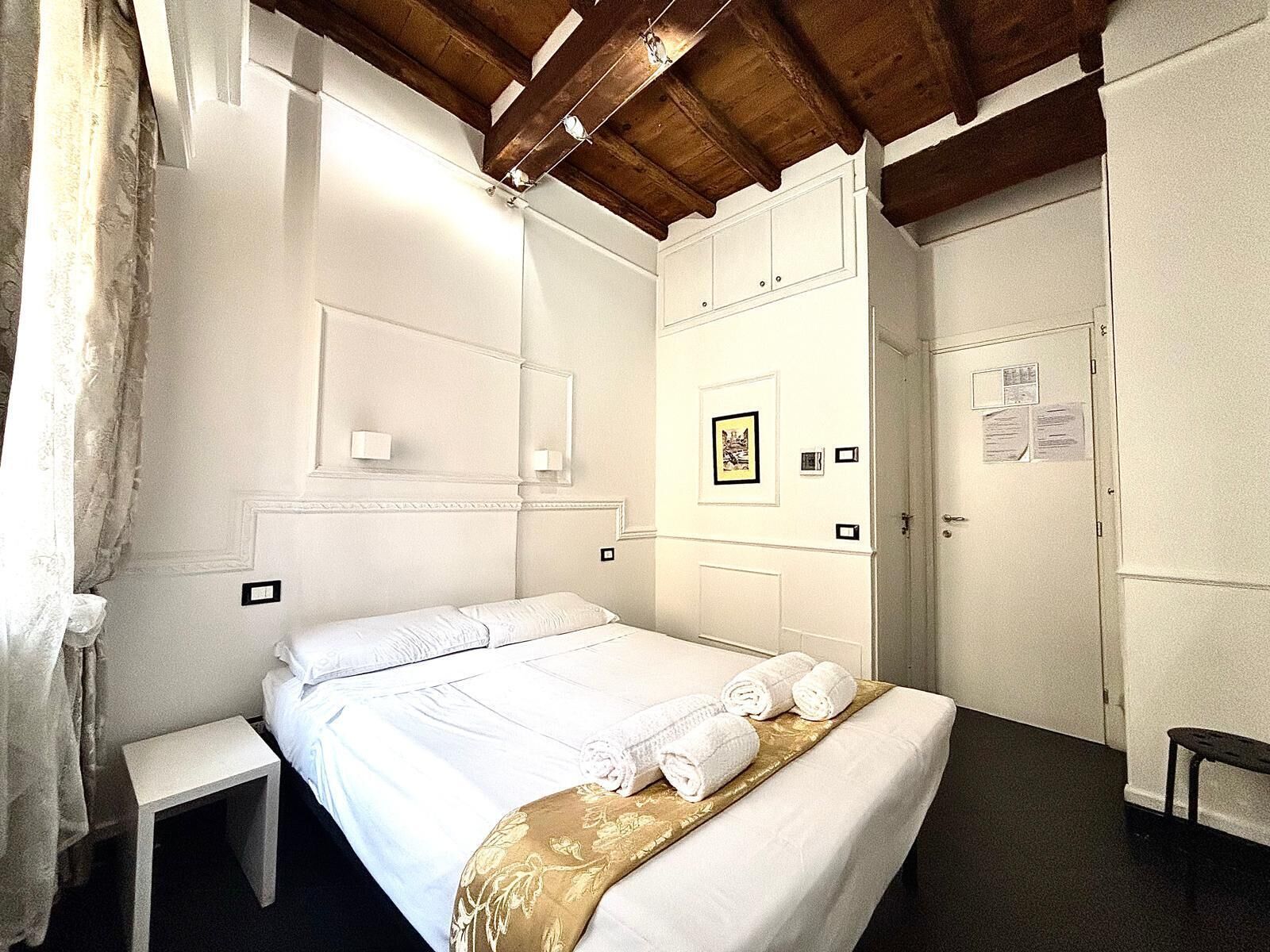 Une chambre d’hôtel comprenant un lit, une table de chevet, une armoire et une porte sur laquelle est affiché un avis.