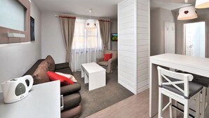 Una sala de estar moderna y bien iluminada con sofá, mesa de centro y comedor con una mesa y sillas blancas.