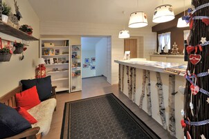 Un rincón acogedor con un banco de madera, una estantería y un árbol decorativo.
