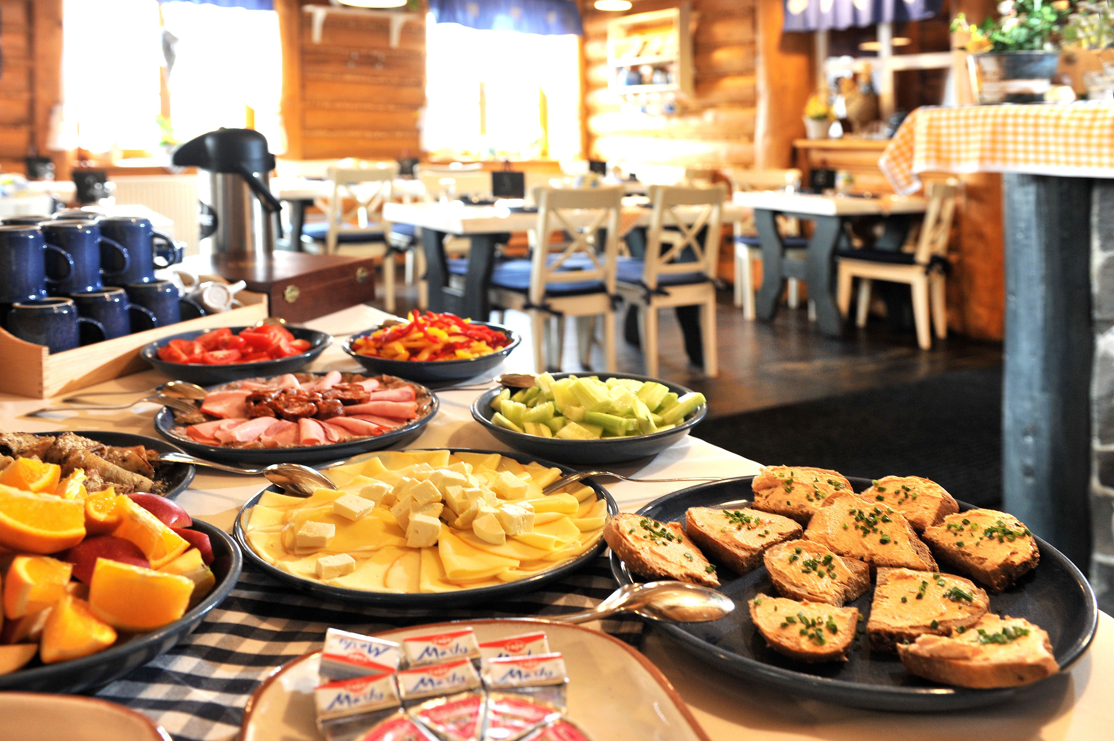 A buffet with various dishes including fruits, meats, and cheeses.