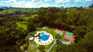 An aerial view of a resort with a central pool, tennis courts, and a walking path. - Hotel Nacional Inn Araxá (Araxá)