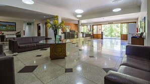 A spacious lobby with a reception desk, seating area, and a large window offering a view of greenery. - Hotel Nacional Inn Araxá (Araxá)