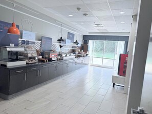 A modern breakfast area with a counter, display cases, and a large window offering a view of the outdoors. - Holiday Inn Express & Suites Bonham by IHG (Bonham)
