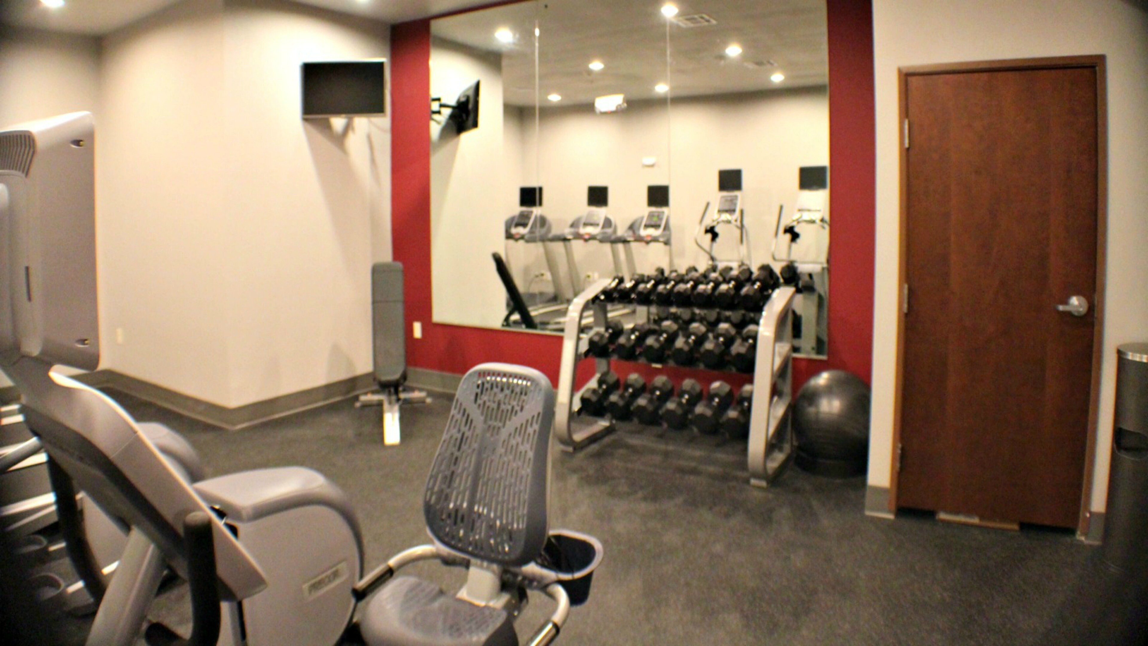 A gym with exercise equipment, a treadmill, and a chair.