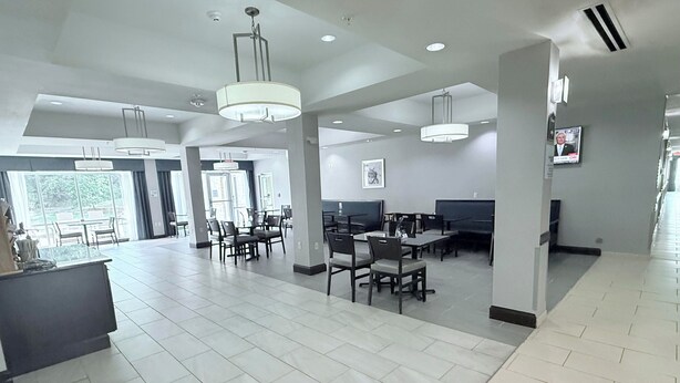 A spacious hotel lobby with high ceilings, modern chandeliers, and a central seating area with tables and chairs. - Holiday Inn Express & Suites Bonham by IHG (Bonham)