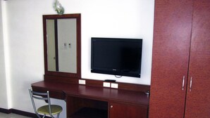A room with a wooden desk, a chair, a television, and a wardrobe. - Nina's Guest House 2 (Patong)