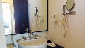 Une salle de bain avec un lavabo blanc, un miroir et une serviette posée sur le comptoir.