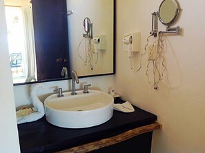 A bathroom with a white sink, a mirror, and a towel on the counter. - Hotel Arenas (Mahahual)