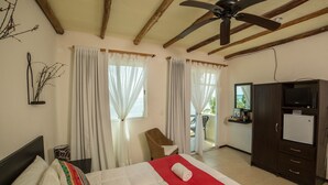 Une chambre d’hôtel comprenant un lit, une chaise, un bureau avec une télévision et un balcon.