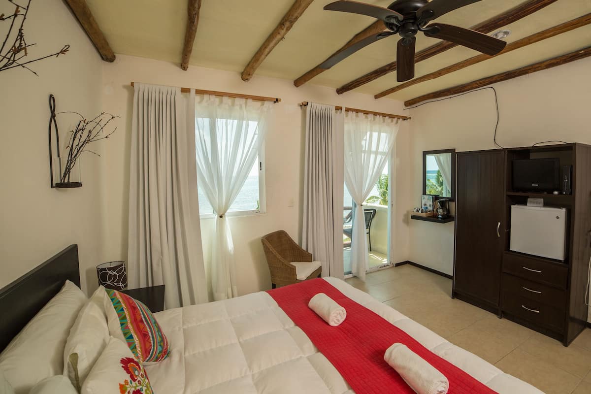 Une chambre d’hôtel comprenant un lit, une chaise, un bureau avec une télévision et un balcon.