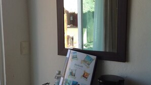 Une petite étagère noire sur laquelle se trouvent un livre, une bouteille et une machine à café.