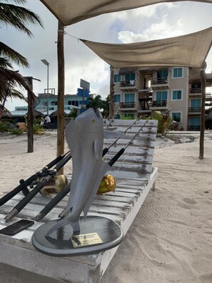 A beachside fishing area with a large fish sculpture, fishing rods, and a water pump.