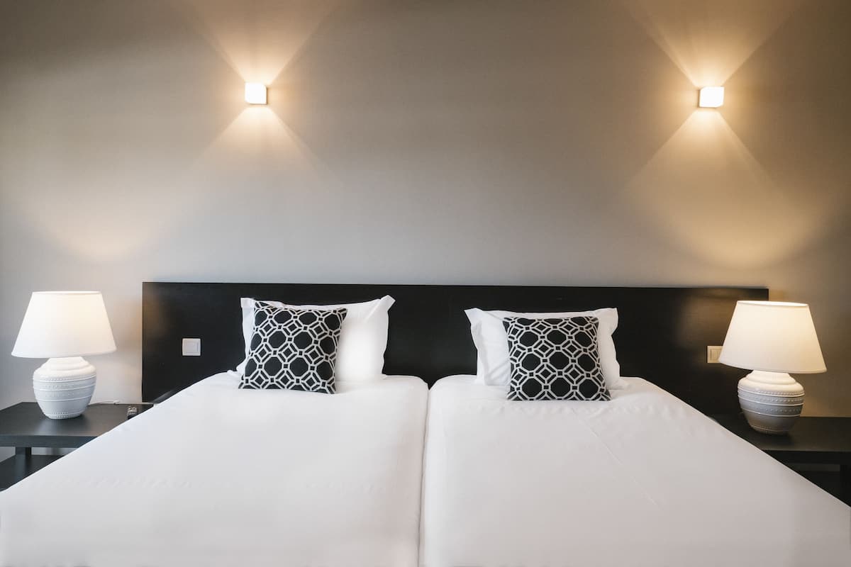 Een hotelkamer met een tweepersoonsbed, twee bedlampjes en twee wandlampen.