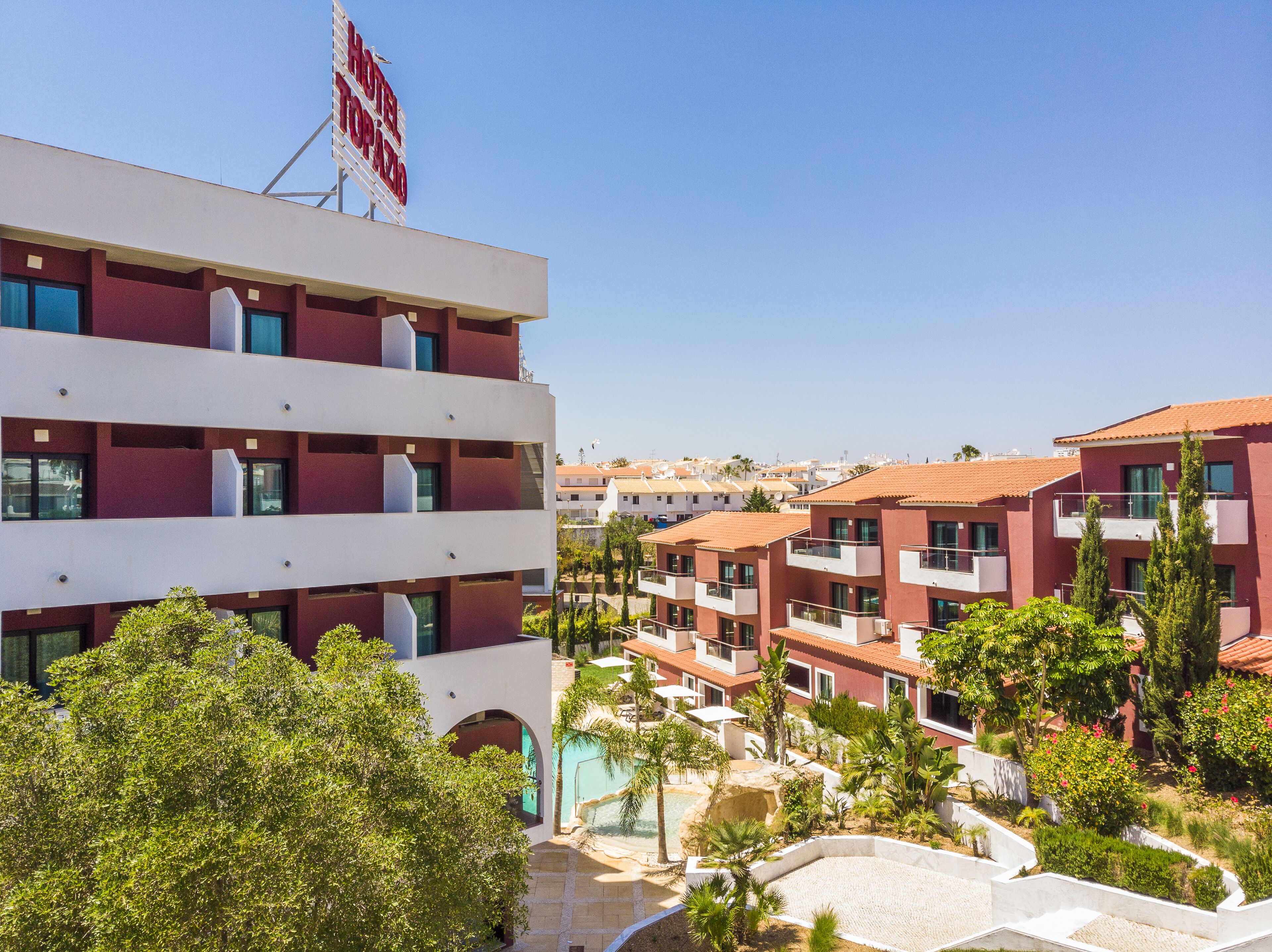 A hotel with multiple balconies, a swimming pool, and a clear view of the surrounding buildings.
