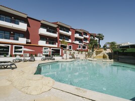 Una piscina al aire libre, sombrillas, sillones reclinables de piscina