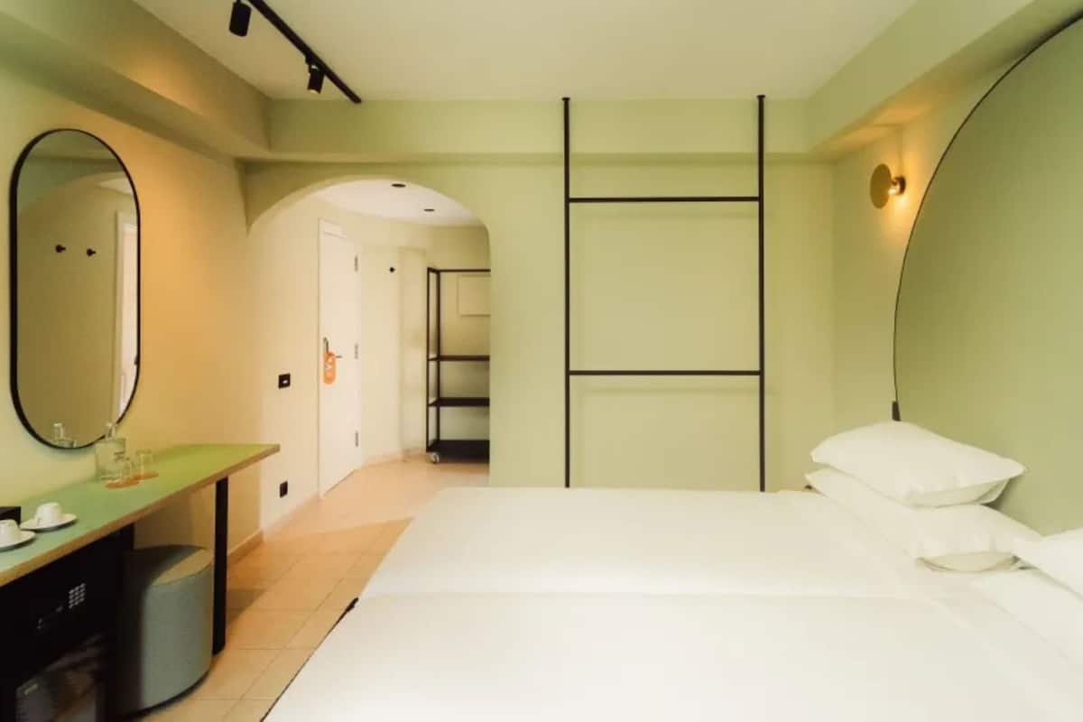 Een slaapkamer met een bed, nachtkastje, spiegel en een garderobe.