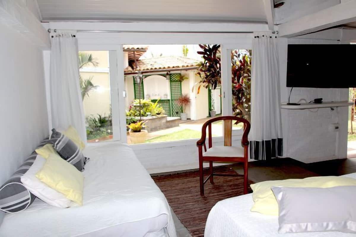 A room with two beds, a chair, and a TV.