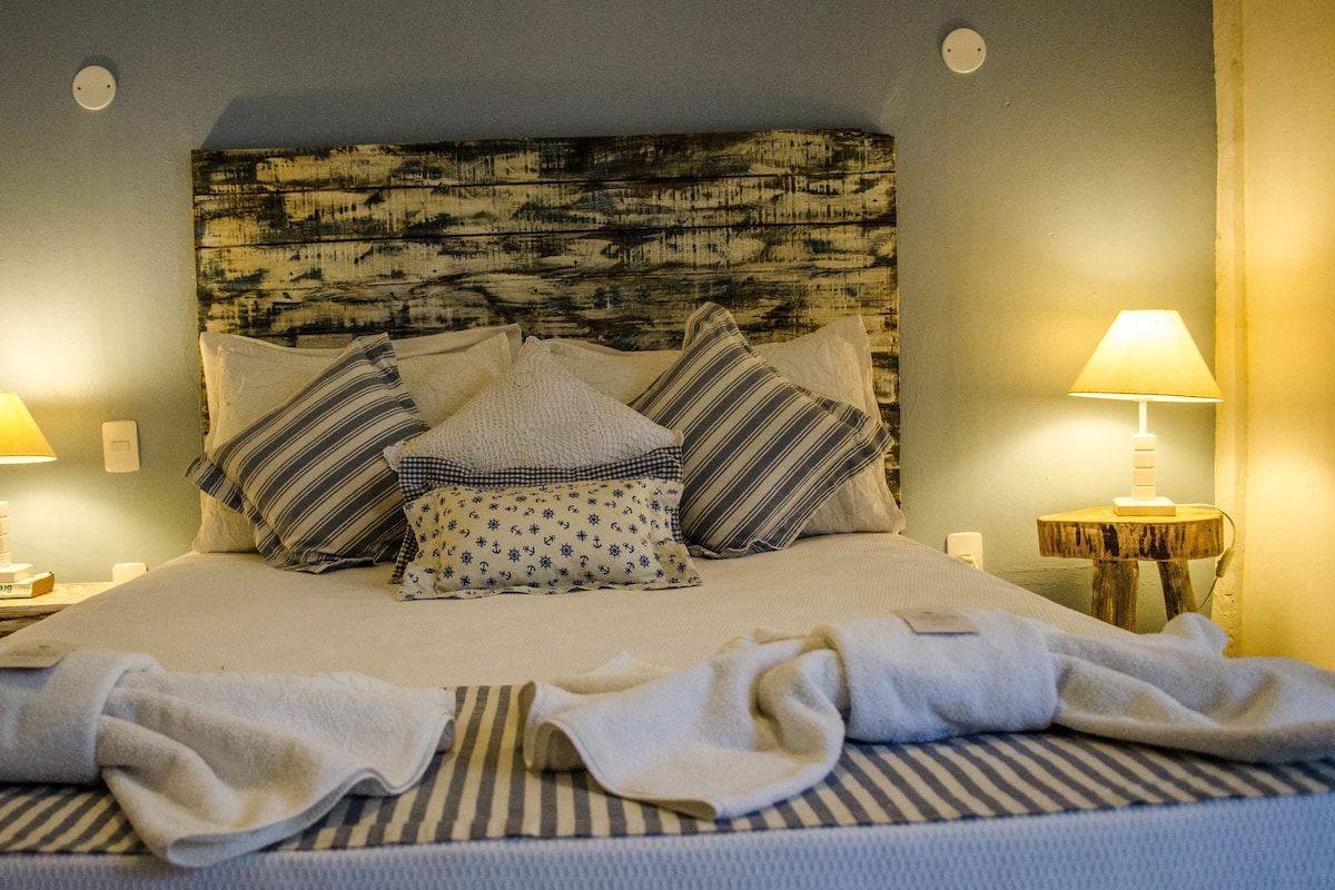 A neatly made bed with striped bedding, a wooden headboard, and two bedside lamps.