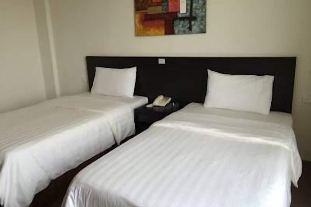 A hotel room with two single beds, a nightstand, and a painting on the wall.