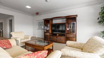 A living room with a television, wooden cabinet, and two sofas with patterned cushions.