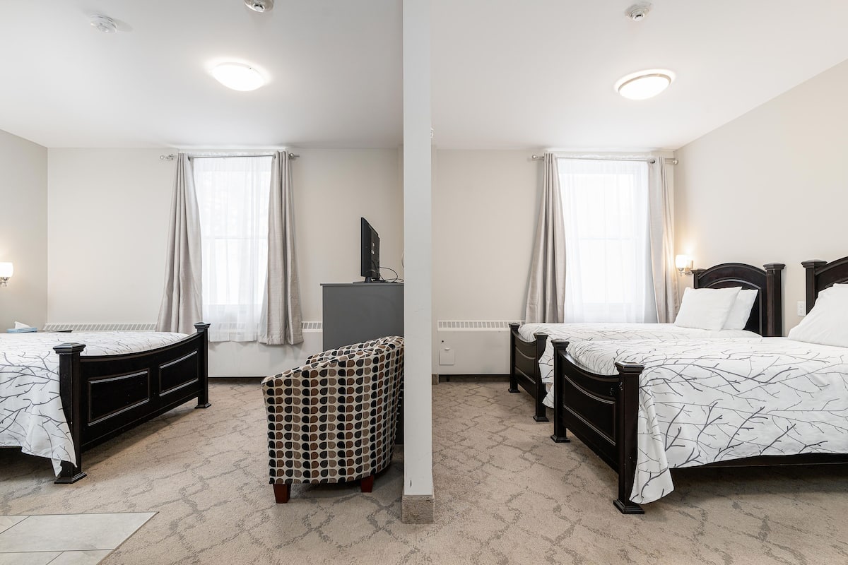 Une chambre d’hôtel avec deux lits, un petit bureau et une chaise.