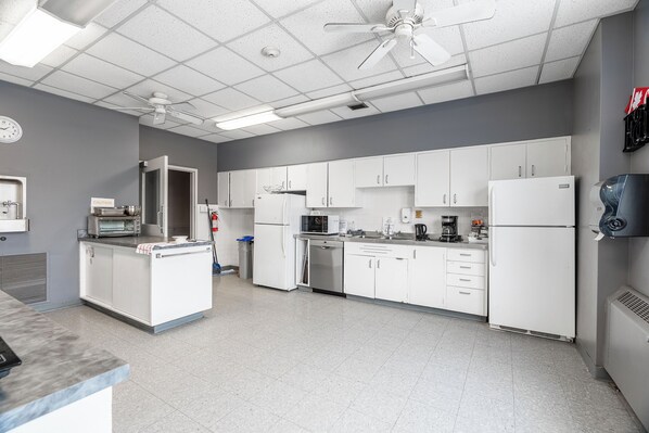 Una cocina moderna con armarios blancos, un microondas, una cafetera y un ventilador de techo.