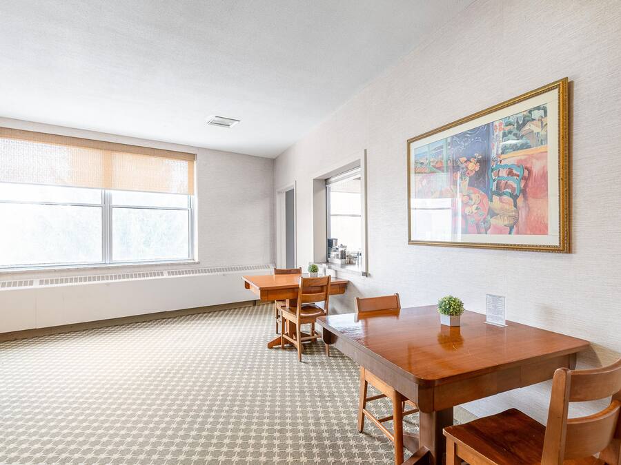 A spacious room with a large window, a wooden dining table, and chairs.