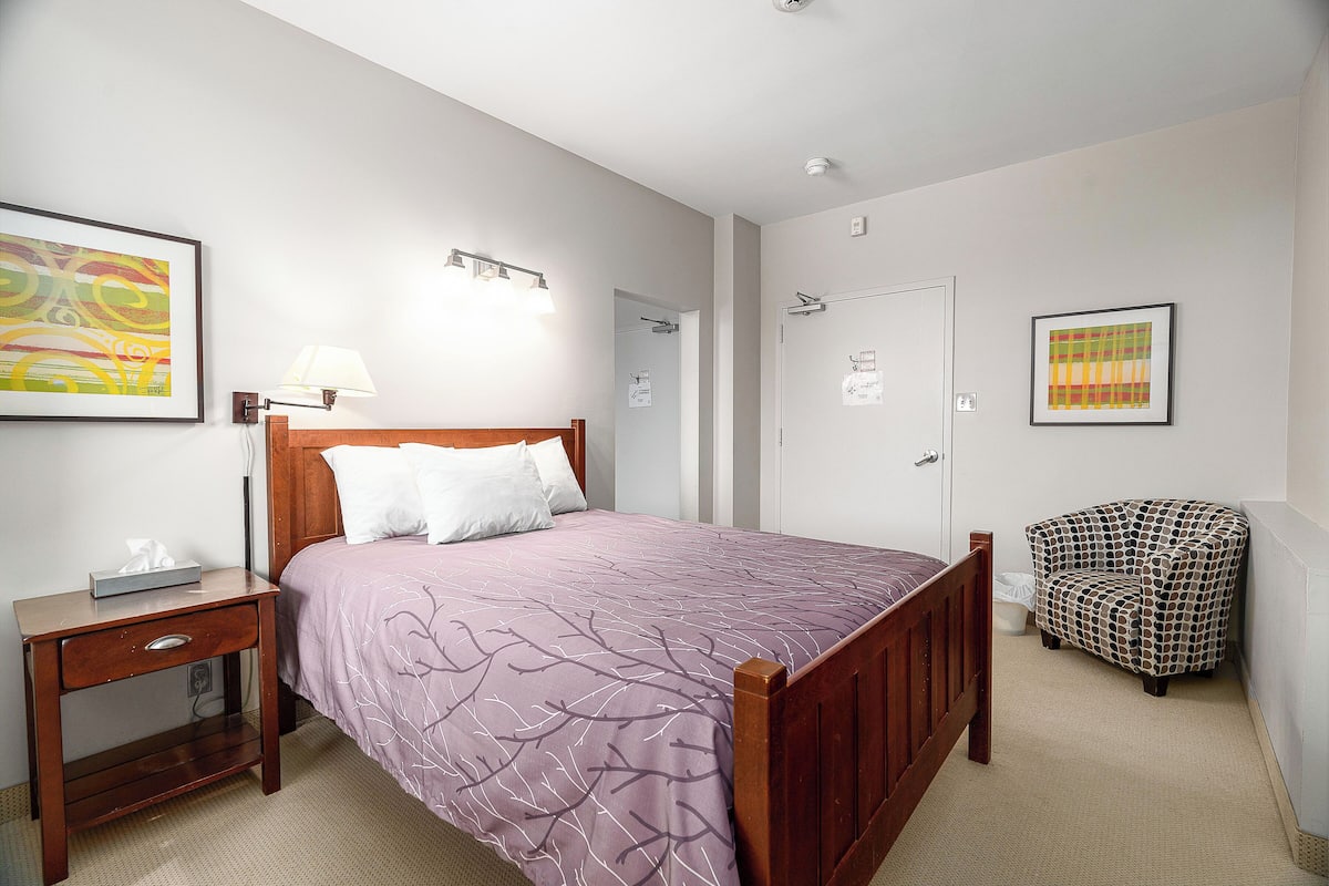Une chambre à coucher avec un lit, une table de chevet, une chaise et une porte.