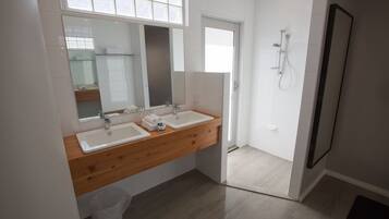 Ein modernes Badezimmer mit zwei Waschbecken, einem großen Spiegel und einer Dusche.