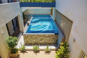 A rooftop swimming pool with a stone surround, surrounded by potted plants. - Maand Up Accommodation (Fremantle)
