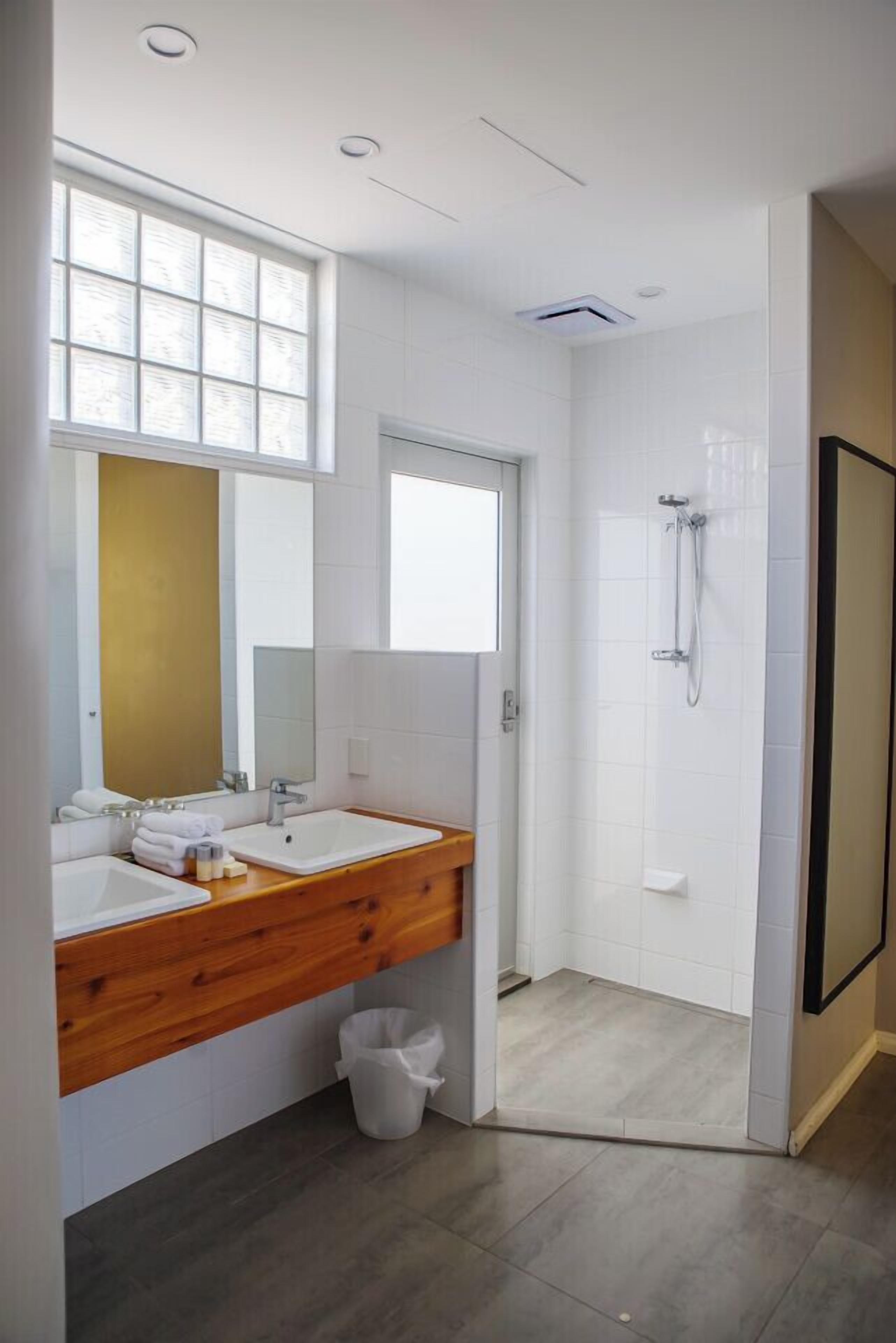 Un baño moderno con dos lavabos, ducha y un espejo grande.