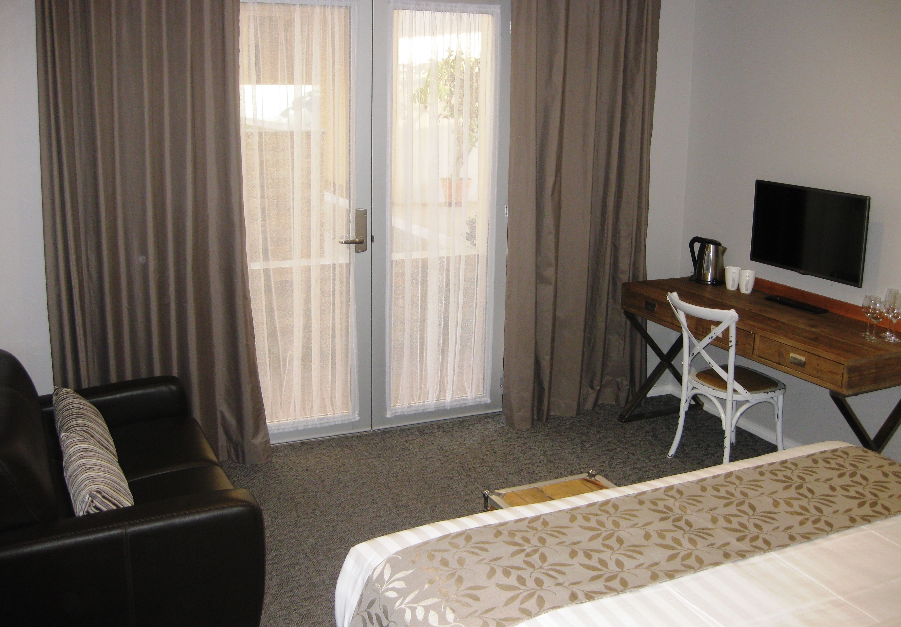 A hotel room with a bed, a desk, a chair, a television, and a window with curtains.