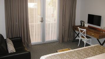 A hotel room with a bed, a desk, a chair, a television, and a window with curtains.