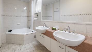 A modern bathroom with a bathtub, two sinks, and a large mirror.