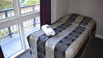 A bed with a patterned bedspread and a rolled-up towel on it.