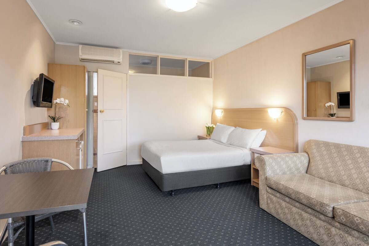 Een hotelkamer met een bed, een slaapbank, een bureau en een televisie.