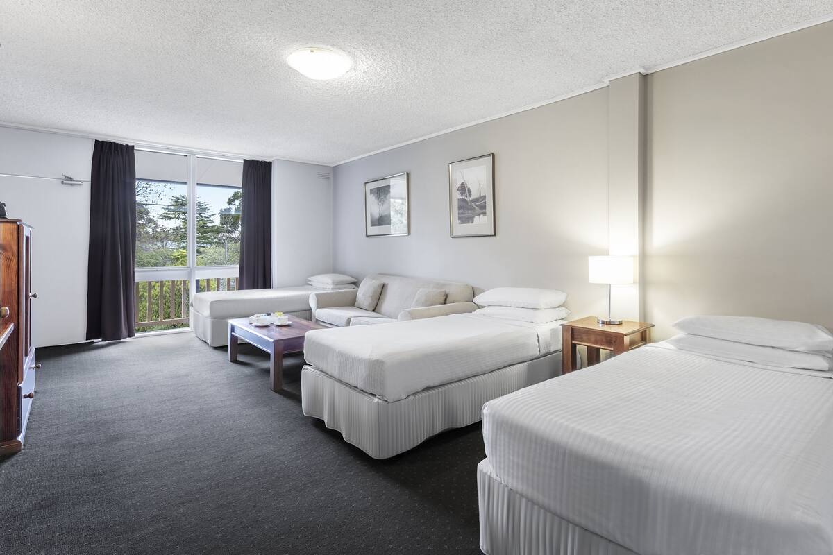 Een hotelkamer met twee bedden, een bank, een kleine tafel en een lamp.